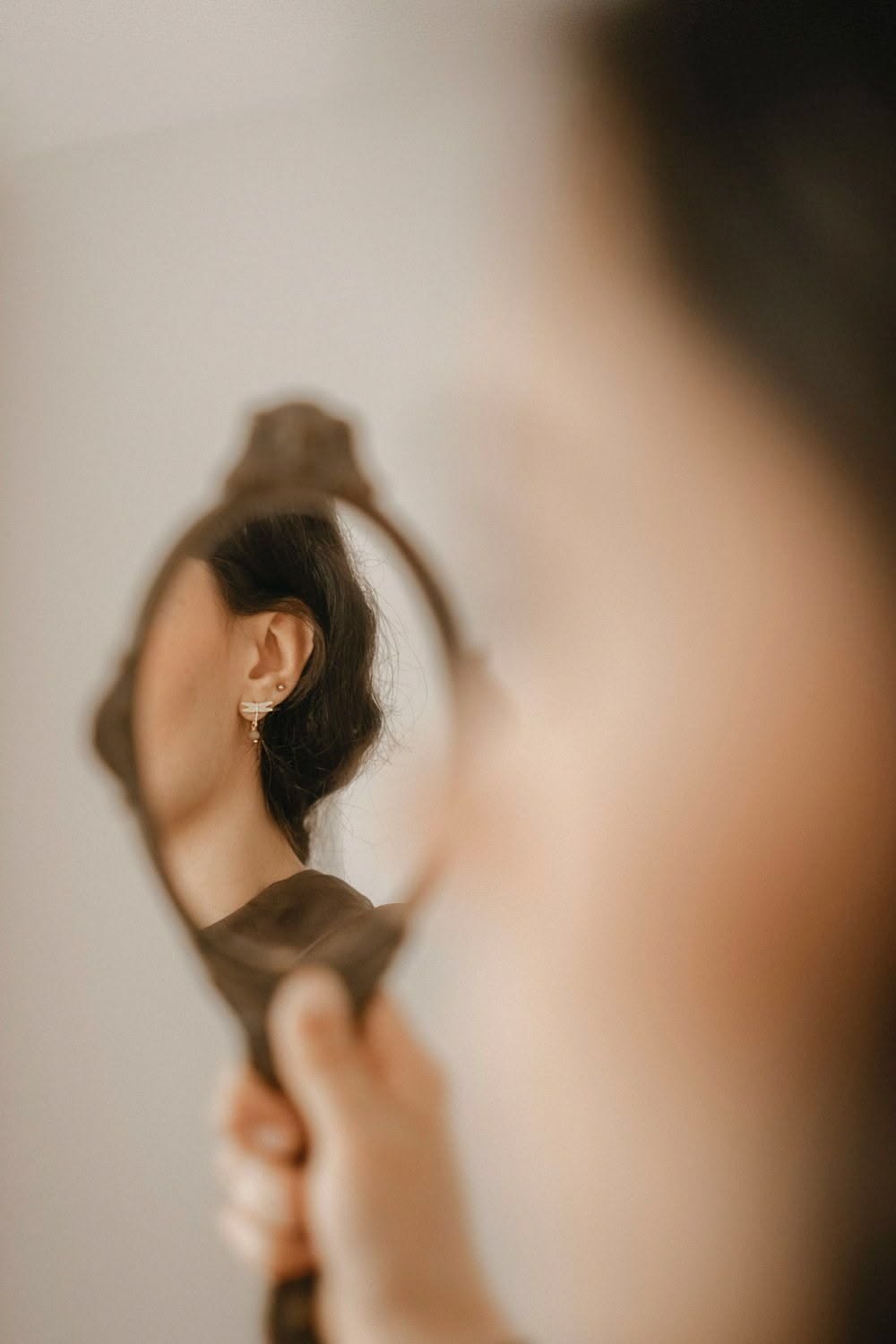 Mulher segurando um espelho de mão, que reflete o seu rosto